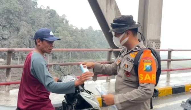 Polda Jatim Bagikan Masker di Jembatan Curah Kobokan Lumajang, Lindungi Warga dari Abu Vulkanik Semeru
